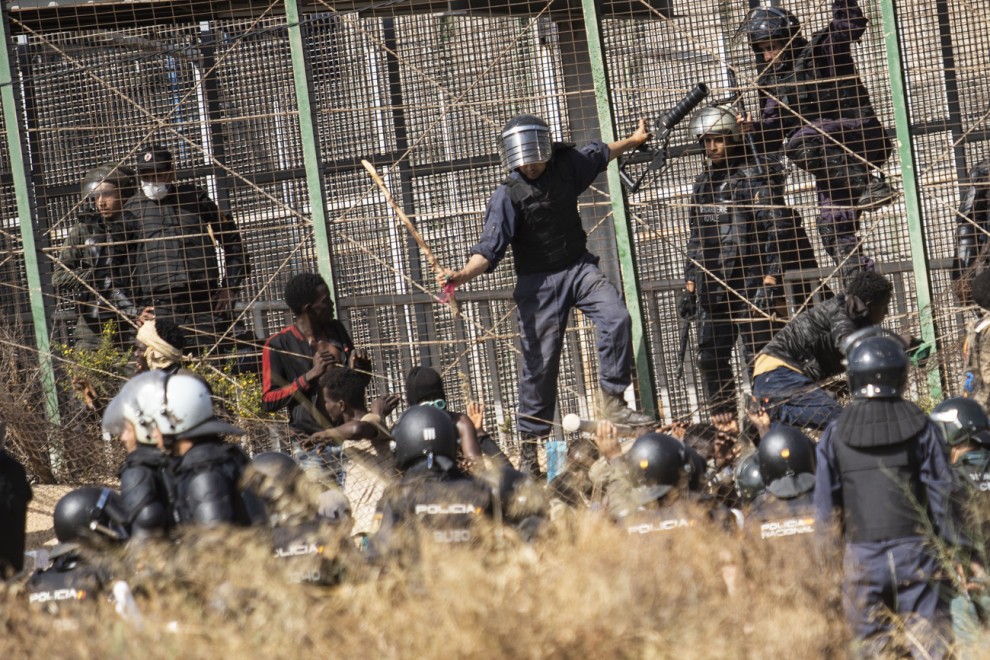 Un agente marroquí golpea desde territorio español con un palo a los migrantes que lograron saltar la valla de Melilla. -Javier Bernardo