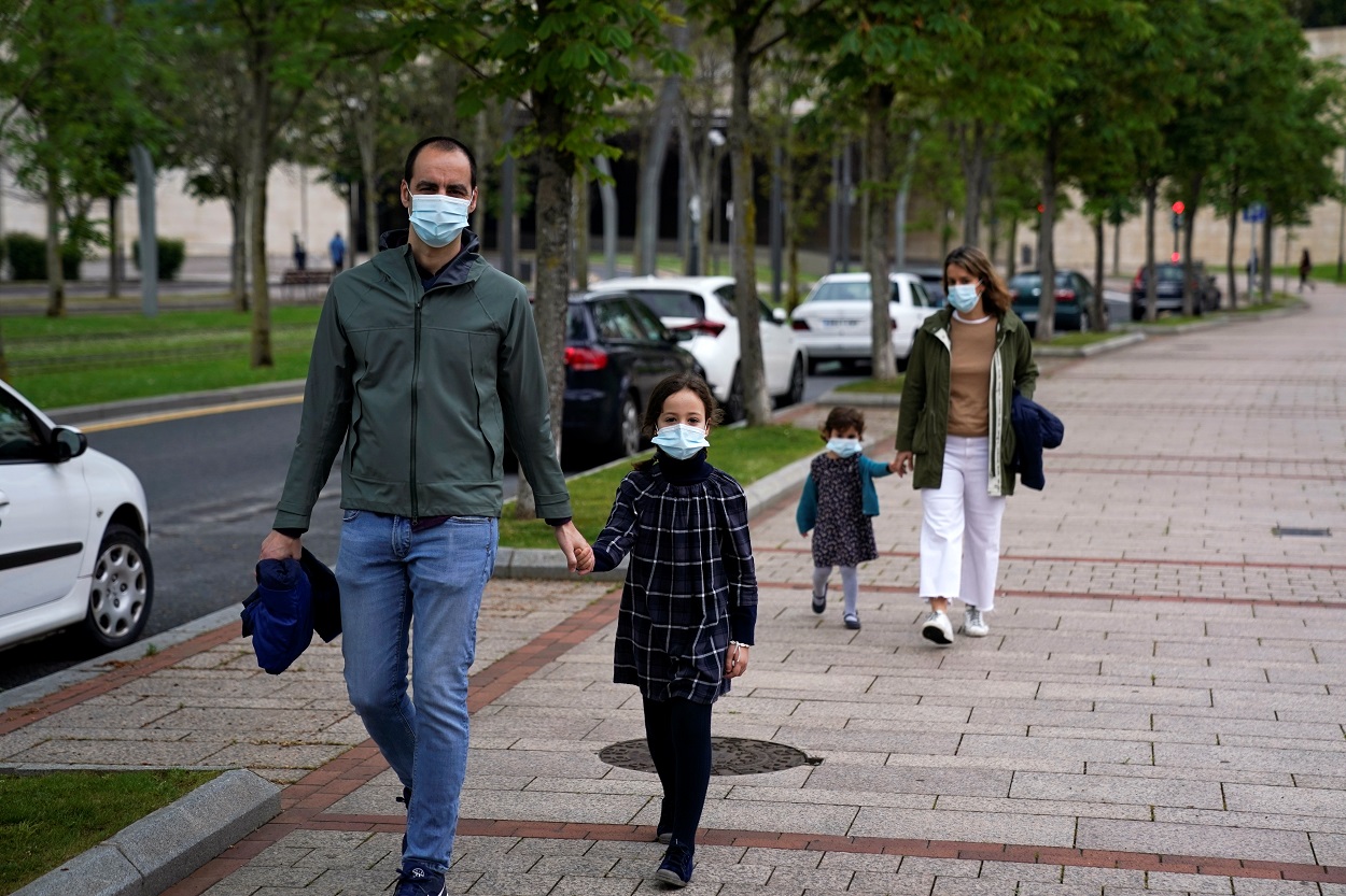 Un matrimonio con sus hijos, todos con mascarilla, dando un paseo en Bilbao. REUTERS/Vincent West