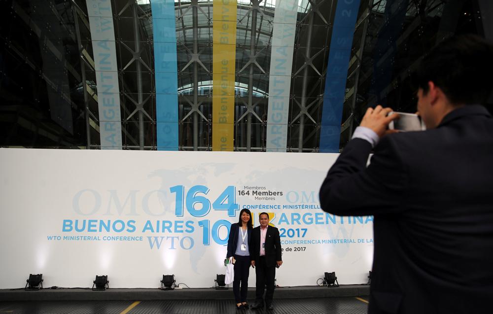 Dos personas posan para una foto en la entrada del centro donde se ha celebrado en Buenos Aires la undécima Conferencia Ministerial de la OMC. REUTERS/Marcos Brindicci