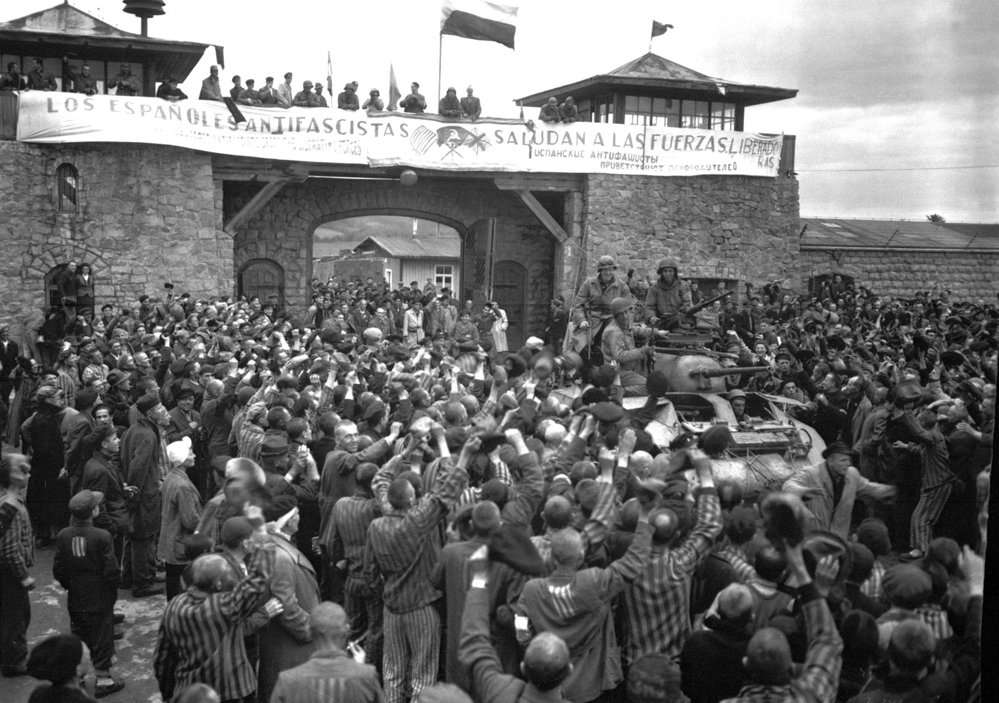 Prisioneros de Mauthausen saludan a la 11ª División Acorazada de los EE UU por su liberación bajo una pancarta escrita en español sobre sábanas.