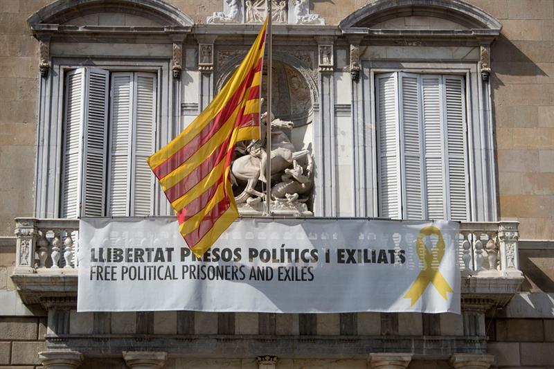 Vista de la fachada del Palau de la Generalitat de donde cuelga, junto a la bandera catalana, un cartel y un lazo amarillo reivindicando la libertad de los políticos encarcelados. EFE/Marta Pérez