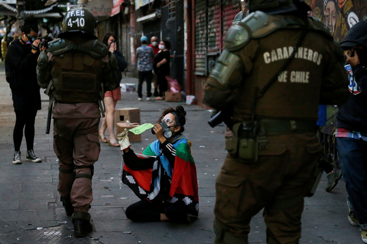 Una manifestante muestra a los policías un cartel que dice: "En Chile se tortura", durante una protesta contra el gobierno en Valparaíso. REUTERS/Rodrigo Garrido
