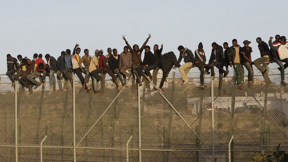 Inmigrantes encaramados a la valla fronteriza de Melilla. EFE
