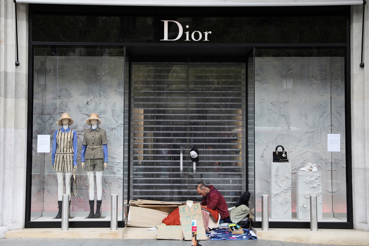 Un sin techo, en la puerta de una tienda de lujo en el Paseo de Gracia de Barcelona, durante la crisis del coronavirus. REUTERS/Nacho Doce