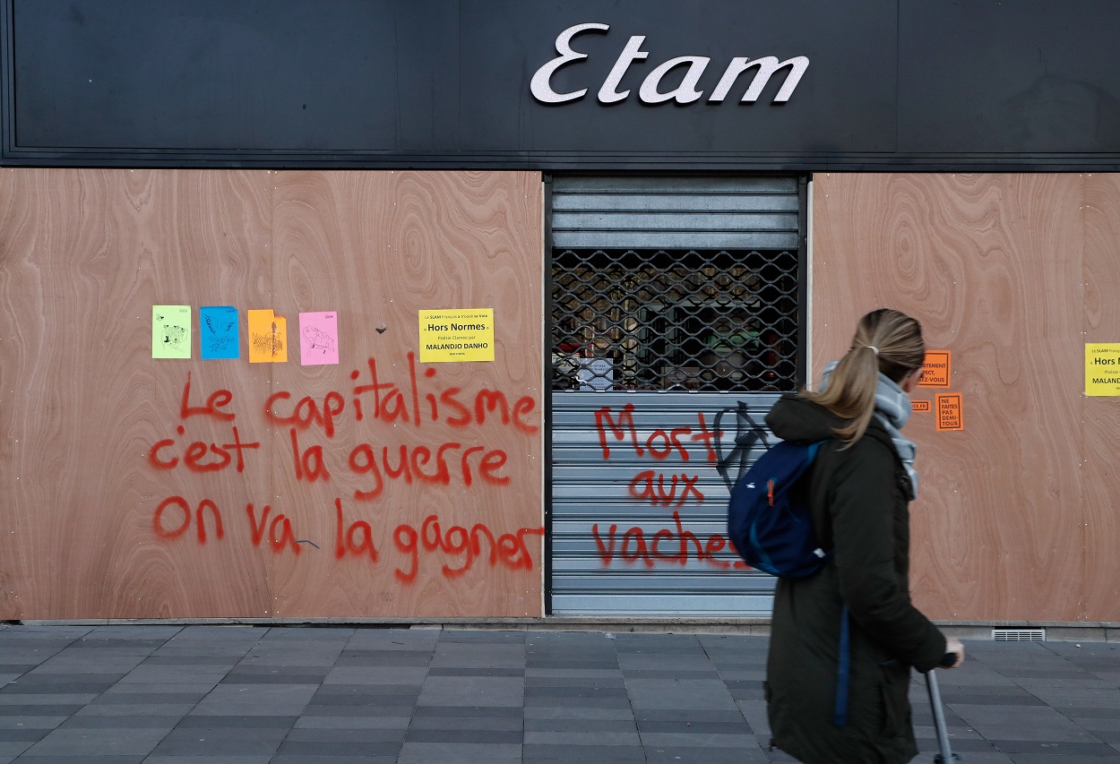 Una joven pasa junto a una pintada en París, que dice "Nosotros ganaremos la guerra contra el capitalismo". AFP/Francois Guillot