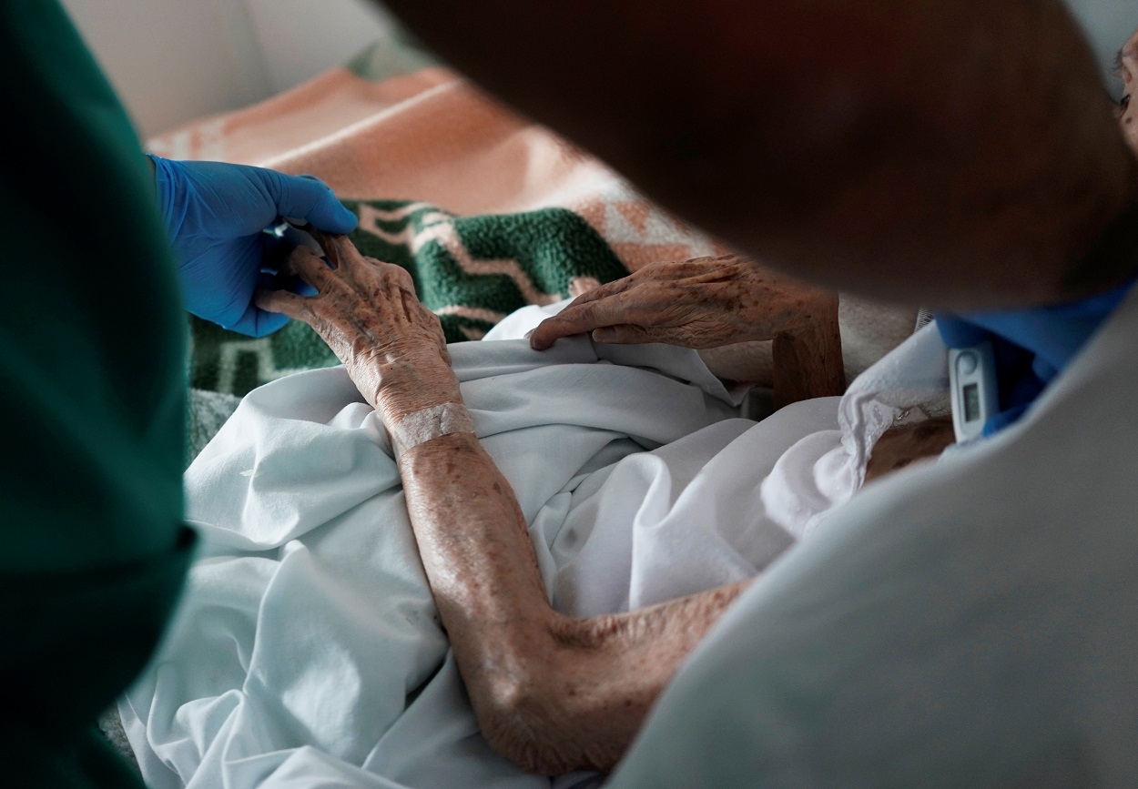 Un sanitario atiende a un anciano en una residencia en la localidad madrileña de Pozuelo de Alarcçon, durante el estado de alarma por la pandemia del coronavirus. REUTERS/Juan Medina
