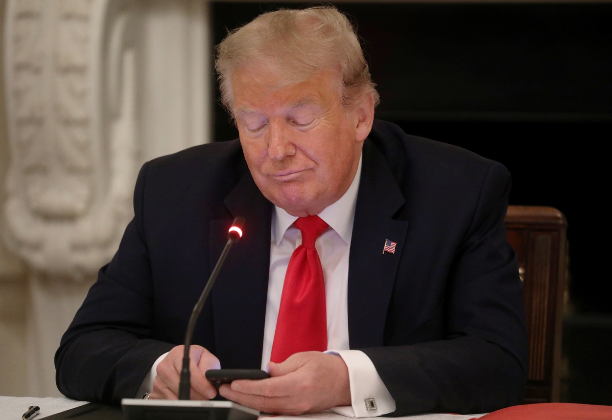 El presidente de EEUU, Donald Trump, mira su teléfono móvil durante una reunión en la Casa Blanca para analizar las medidas para la vuelta a la actividad de las pymes tras la pandemia. REUTERS/Leah Millis