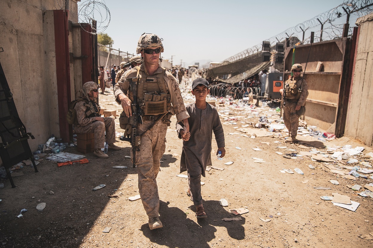 Un marine estadounidense acompaña a un menor junto a su familia para su evacuación, en el aeropuerto de Kabul (Afganistán). REUTERS