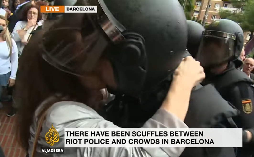 Captura del video de Al Jazeera en el que se ve a una activista besar a uno de los antidisturbios que cargaron en la jornada del 1-0.