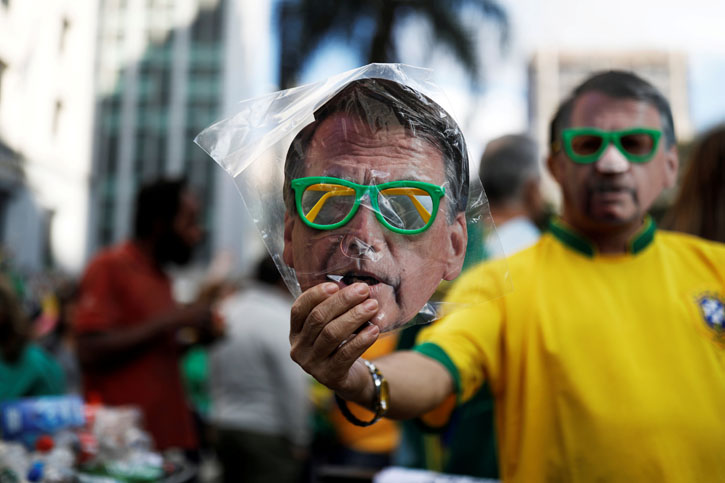 Un vendedor callejero en sao Paulo sostiene una careta con la efigie del candidato ultraderechista Jair Bolsonaro. REUTERS/Nacho Doce