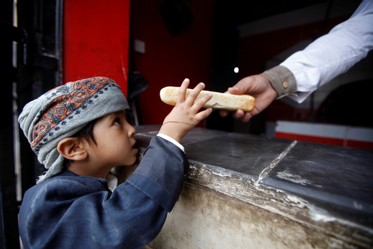 Un niño recibe una pieza de pan en un establecimiento de la ONG Mercy Bakery, en la localidad yemení de Saná. REUTERS/Mohamed al-Sayaghi