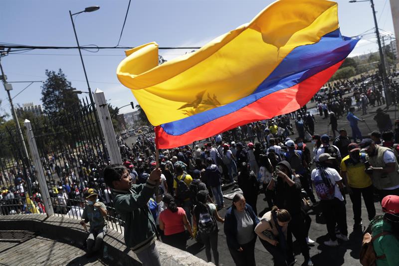 Un niño ondean una gran bandera ecuatoriana frente a decenas de ciudadanos y manifestantes que limpian las calles tras acordar el final de llas protestas contra las medidas del presidente Lenin Moreno. EFE/ Bienvenido Velasco