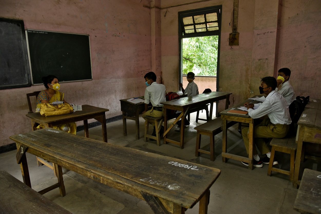 Estudiantes y su profesora con mascarilla en un aula de una escuela de la localidad de Guwahati, en el estado nororiental de Assam, en India. REUTERS/David Talukdar