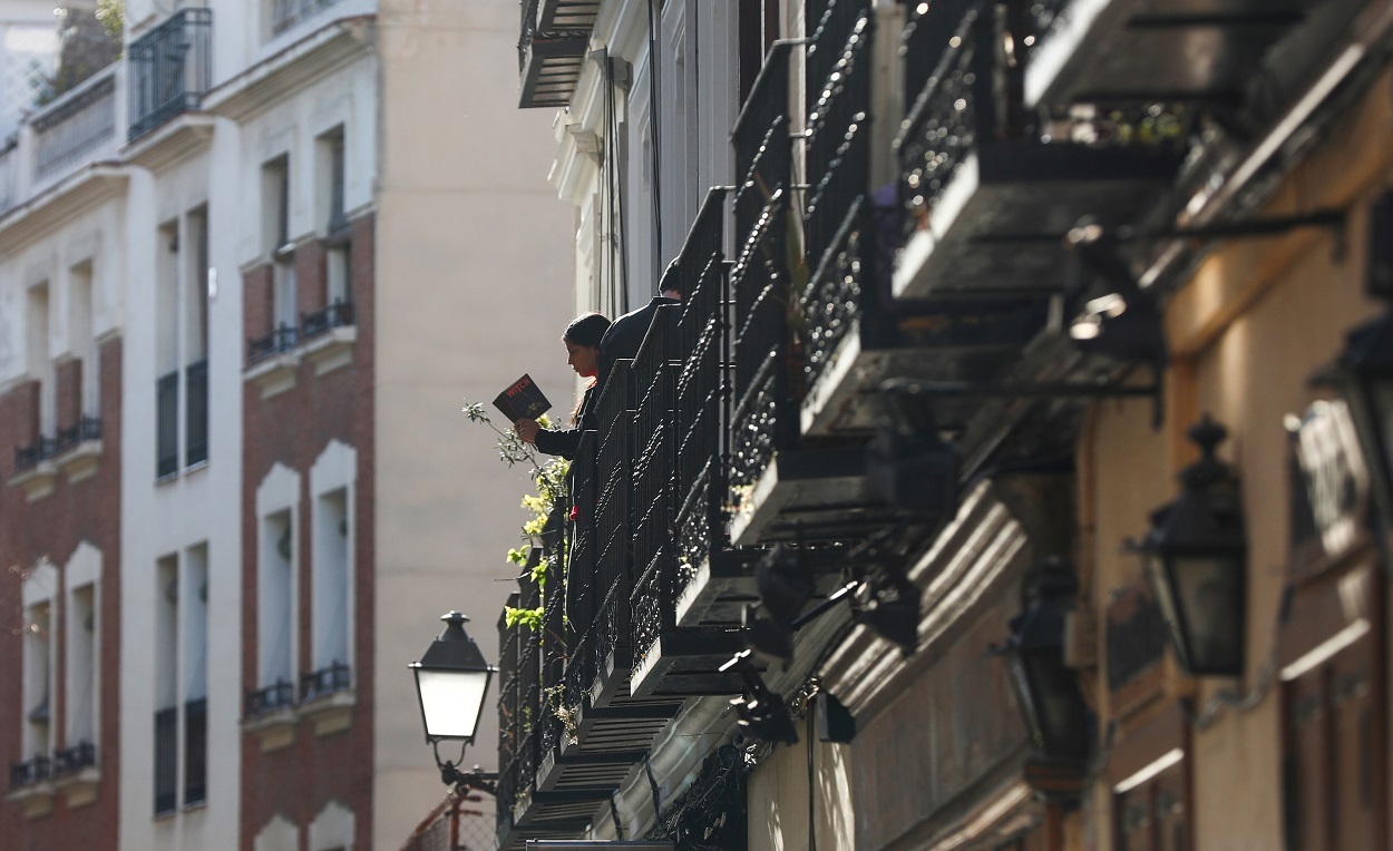 Una joven lee un libro en un balcón durante la pandemia del coronavirus en Madrid. / SERGIO PÉREZ (REUTERS)