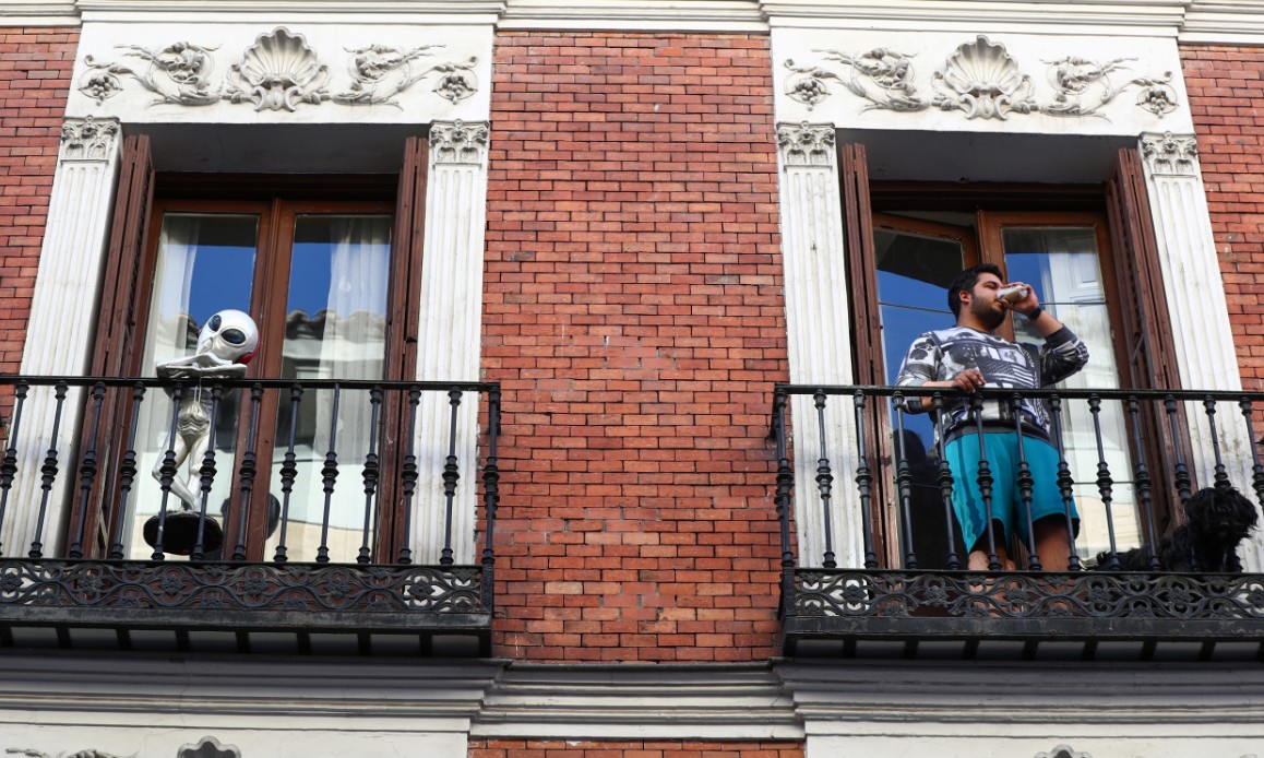Un hombre toma un café junto a un alien sin identificar durante la cuarentena por el coronavirus en Madrid. / SERGIO PÉREZ (REUTERS)