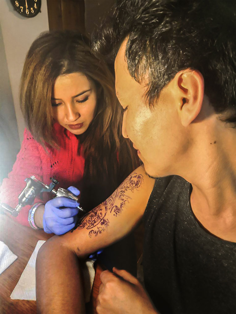 Raha tatuando a Ahmad, un refugiado afgano