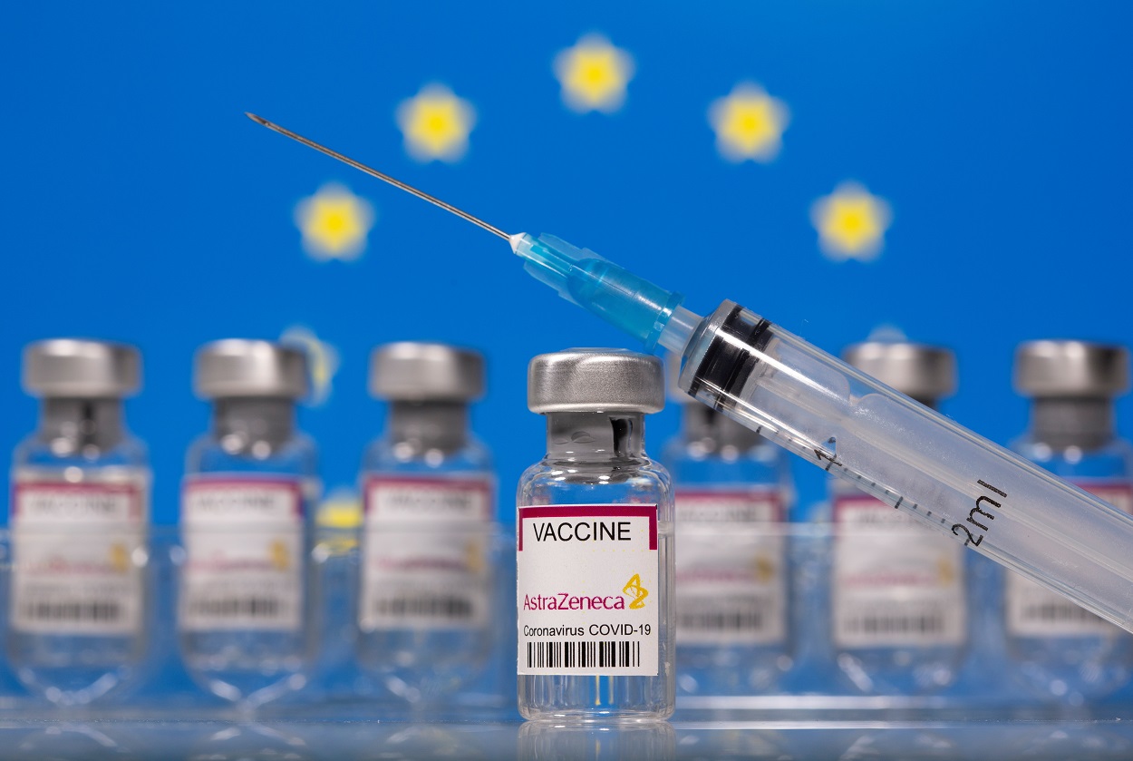 Un vial de vacunas etiquetado con el nombre de Astra-Zeneca, con una jeringuilla, y la bandera de la UE al fondo. REUTERS/Dado Ruvic/Ilustración