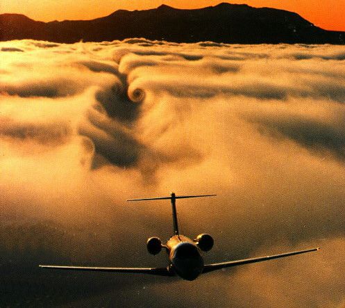 Avión pasando cerca de una capa de nubes, lo que evidencia el downwash y los vórtices.