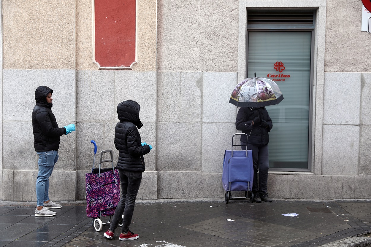 Varias personas guardan cola, manteniendo la distancia de seguridad, junto a un centro de Cáritas en Madrid. REUTERS/Sergio Perez