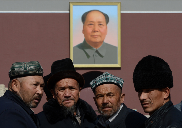 Chinos musulmanes de la etnia uigur, frente al retrato de Mao Zedong, en la Plaza Tiananmen de Pekín, en una foto de marzo de 2013. AFP/Mark RALSTON