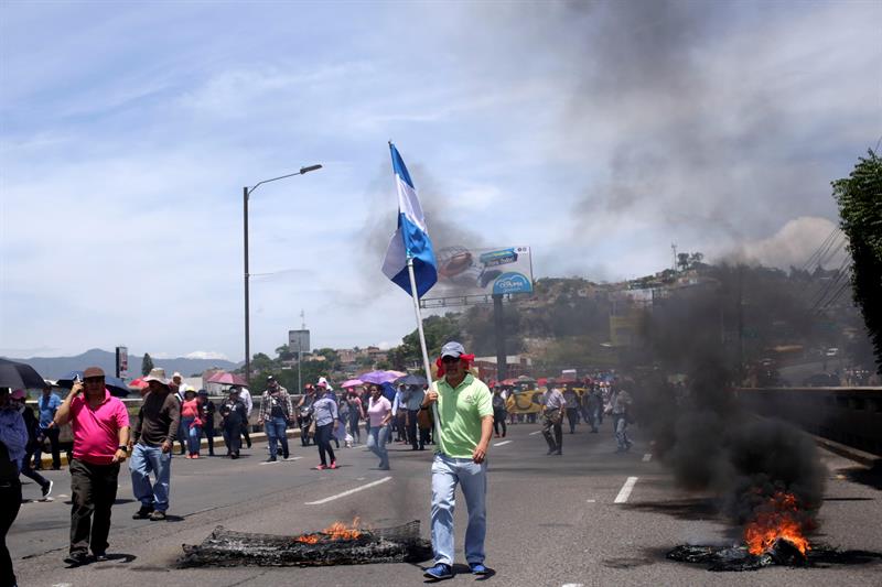 Manifestantes se enfrentan a la policía de Honduras durante una protesta exigiendo la salida del presidente, Juan Orlando Hernández, señalado por la Fiscalía de Nueva York en una presunta conspiración para usar dinero del narcotráfico con el fin de mantenerse en el poder. EFE/ Gustavo Amador