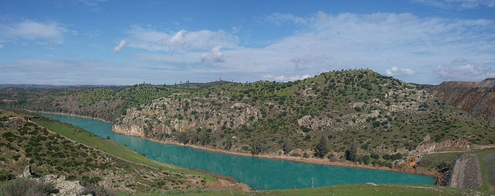 Río Agrio a la altura del municipio de Aznalcóllar. El color turquesa se debe a la contaminación residual que proviene de las escorrentías de las escombreras de las antiguas minas de pirita (a la derecha). Wwal/Wikimedia Commons, CC BY-SA