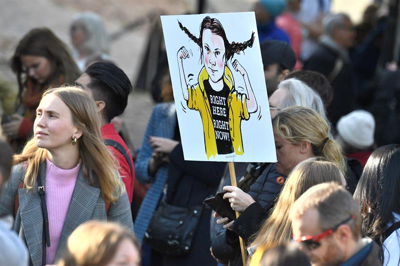Jóvenes manifestantes en el centro de Estocolmo, en la jornada de huelga estudiantil por la crisis climática, llevan una pancarta con la imagen de la activista Greta Thunberg, impulsora del movimiento Friday For Future. EFE / EPA / Claudio Bresciani