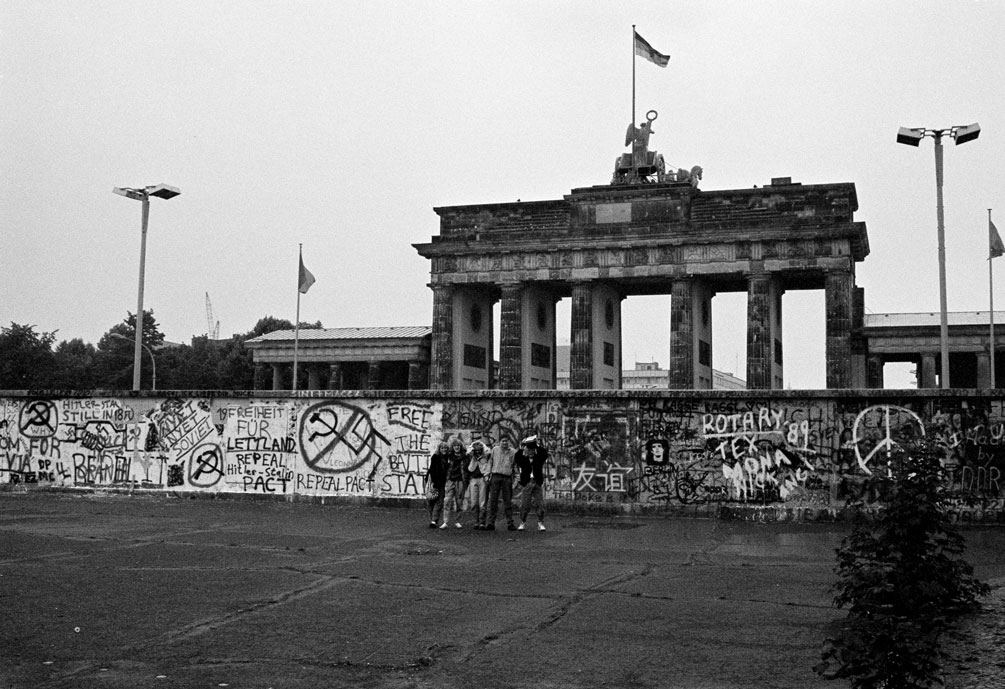 Foto de archivo de un grupo de turistas posa junto al Muro de Berlín, cerca de la Puerta de Brandenburgo, en junio de 1989. REUTERS/Fabrizio Bensch