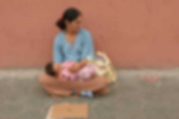 Una mujer con un bebé en el regazo en una calle de Barcelona en 2005. Se ha aplicado un filtro borroso para preservar sus identidades. Michael von Aichberger / Shutterstock