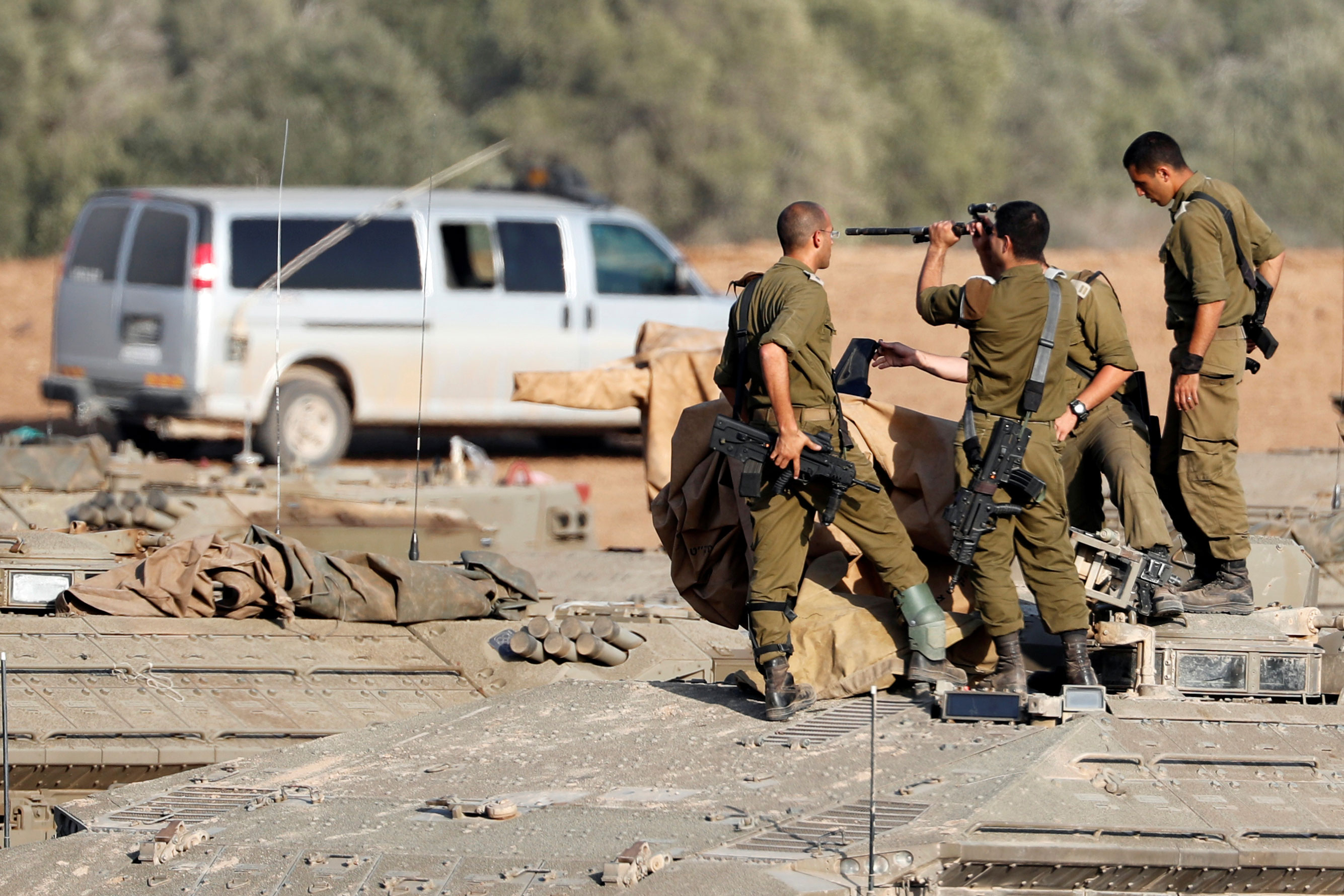 Los soldados israelíes revisan sus armas encima de un vehículo blindado de transporte de personal cerca de la frontera con Gaza, en el sur de Israel. REUTERS / Ronen Zvulun