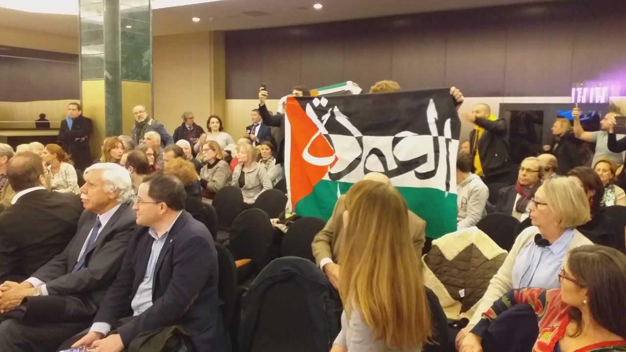 Los activista por los DDHH en Palestina muestran una pancarta durante el acto de Vox.