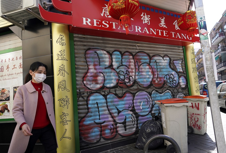 Una mujer con mascarilla pasa junto a un restaurante chino cerrado, en el barrio madrileño de Usera. REUTERS/Juan Medina