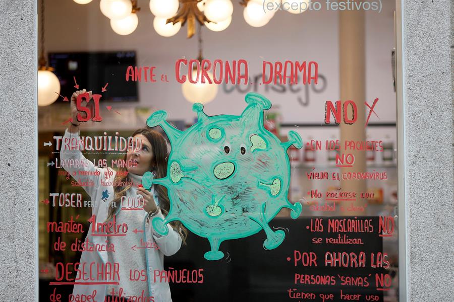 Noelia, trabajadora y autora de la obra gráfica en el escaparate de la farmacia La Salud de Lugo, cuyo leit motiv es el coronavirus. EFE/ Eliseo Trigo