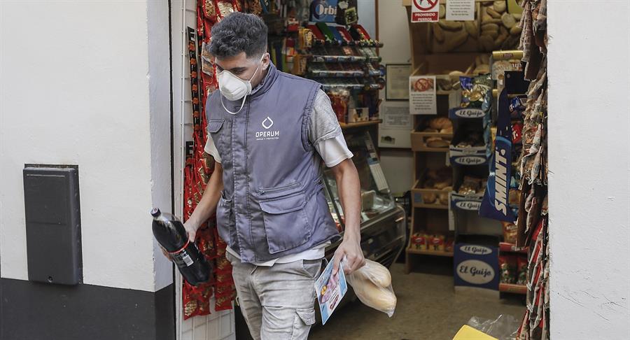 Un trabajador de una obra comprando en una tienda de alimentación de Sevilla en el primer día laborable tras la declaración de estado de alarma por la pandemia de coronavirus COVID-19. EFE/José Manuel Vidal