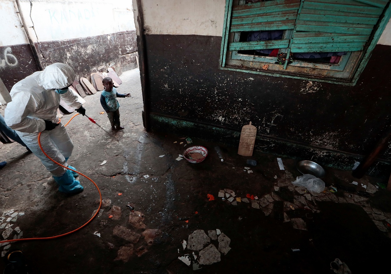 Un niño observa a un miembro de los servicios locales de higiene, con traje de protección y mascarilla, mientras desinfecta una escuela escuela coránica, en Dakar, Senegal. REUTERS / Zohra Bensemra