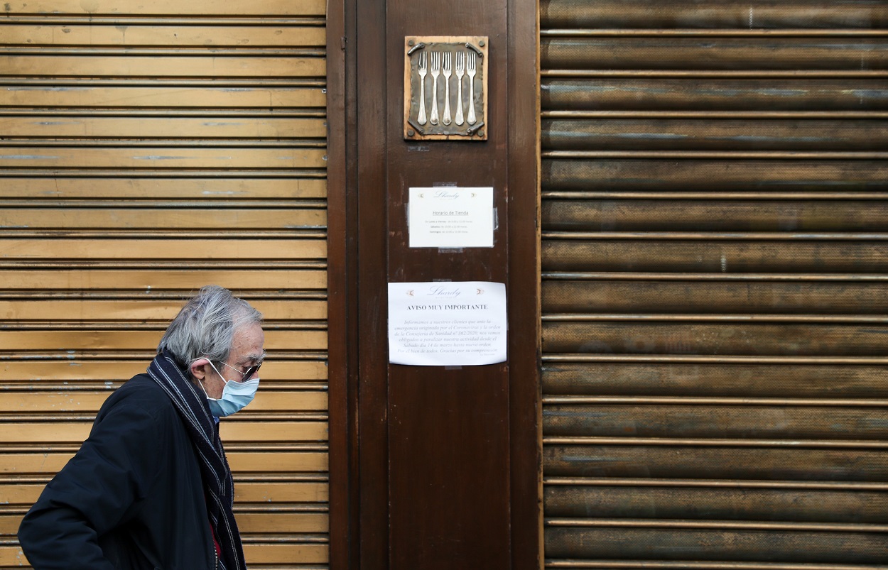 Un anciano con mascarilla pasa delante de un restaurante de cinco tenedores, en el centro de Madrid, cerrado por el estado de alarma por el coronavirus. REUTERS/Susana Vera