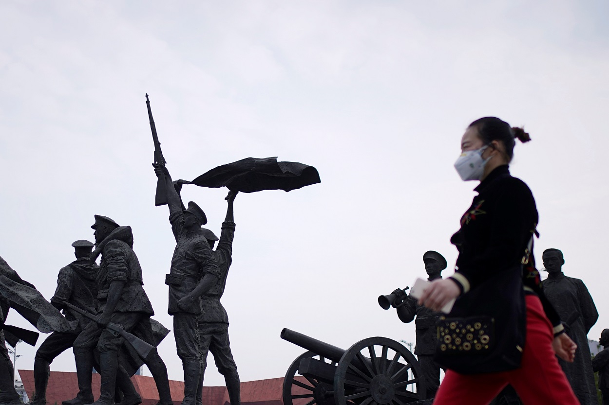 Una mujer con mascarilla pasa por delante del monumento que simboliza la Revolución Xinhai que derrocó al último emperador de China en 1911, en la localidad de Wuhan, el epicentro del coronavirus. REUTERS / Aly Song