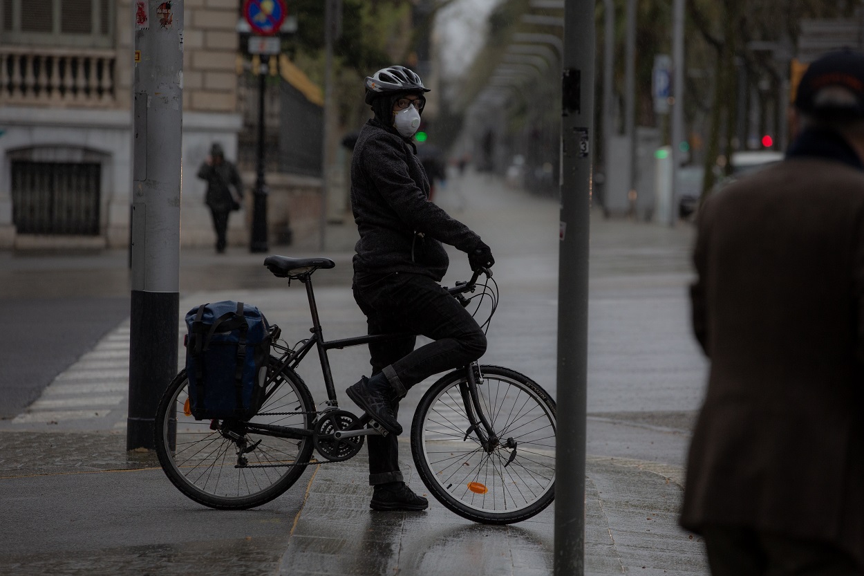 Una persona monta en bicicleta y se protege con una mascarilla en Barcelona. E.P./David Zorrakino