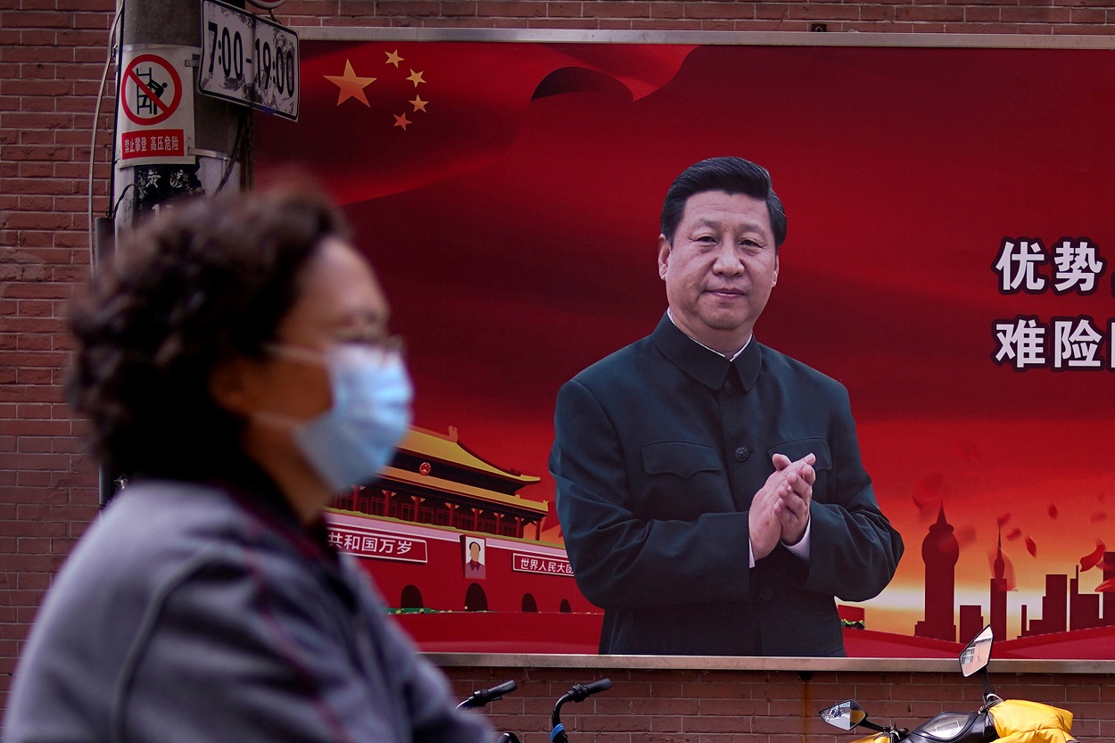 Una mujer con mascarilla pasa por delante de un cartel con el retrato del presidente chino Xi Jinping en una calle de Sahnghai. REUTERS/Aly Song