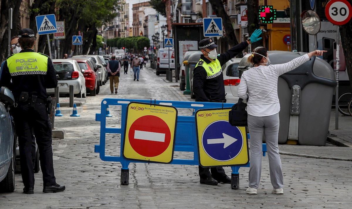 Una mujer consulta a un policía local en una de las calles peatonalizadas del sevillano barrio de Triana, con el fin de evitar las aglomeraciones en las aceras. EFE/José Manuel Vidal
