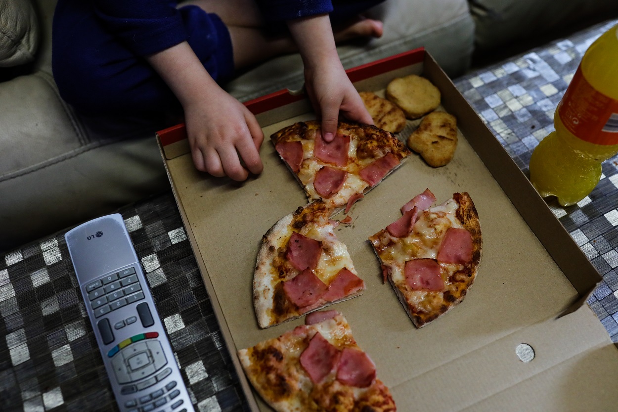 Un niño come un trozo de pizza del menú infantil de Telepizza en su casa. E.P./Jesús Hellín