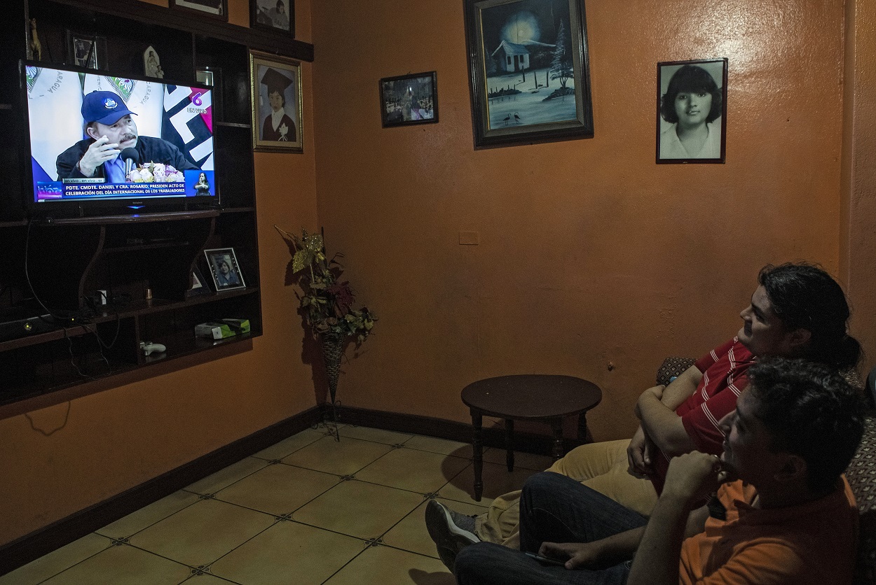 Dos hombres en su casa viendo por televisión la intervención del presidente de Nicaragua, Daniel Ortega, en Managua. AFP/INTI OCON