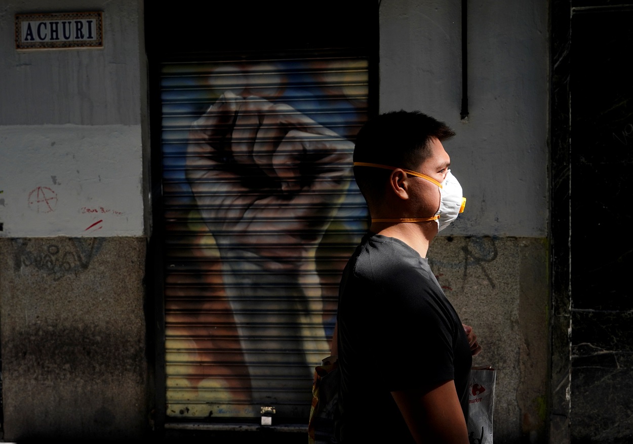 Un hombre con mascarilla pasa por delante de un comercio cerrado en Madrid. REUTERS/Juan Medina