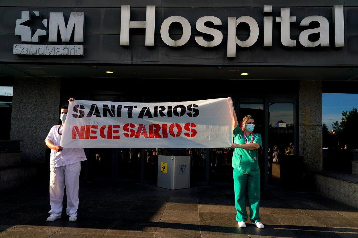 Dos trabajadores sanitarios del Hospital La Paz de Madrid sostienen una pancarta en la que reclaman más personal y medios. REUTERS/Juan Medina