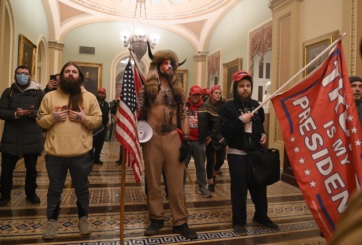 En el centro de la imagen, vestido con pieles, Jake Angeli, miembro del movimiento de teorías de la conspiración Qanon, y que se hace llamar 'Yellowstone Wolf', con otros seguidores de Donald Trump, en su asalto al Capitolio de EEUU, en Washington. AFP/Saul LOEB