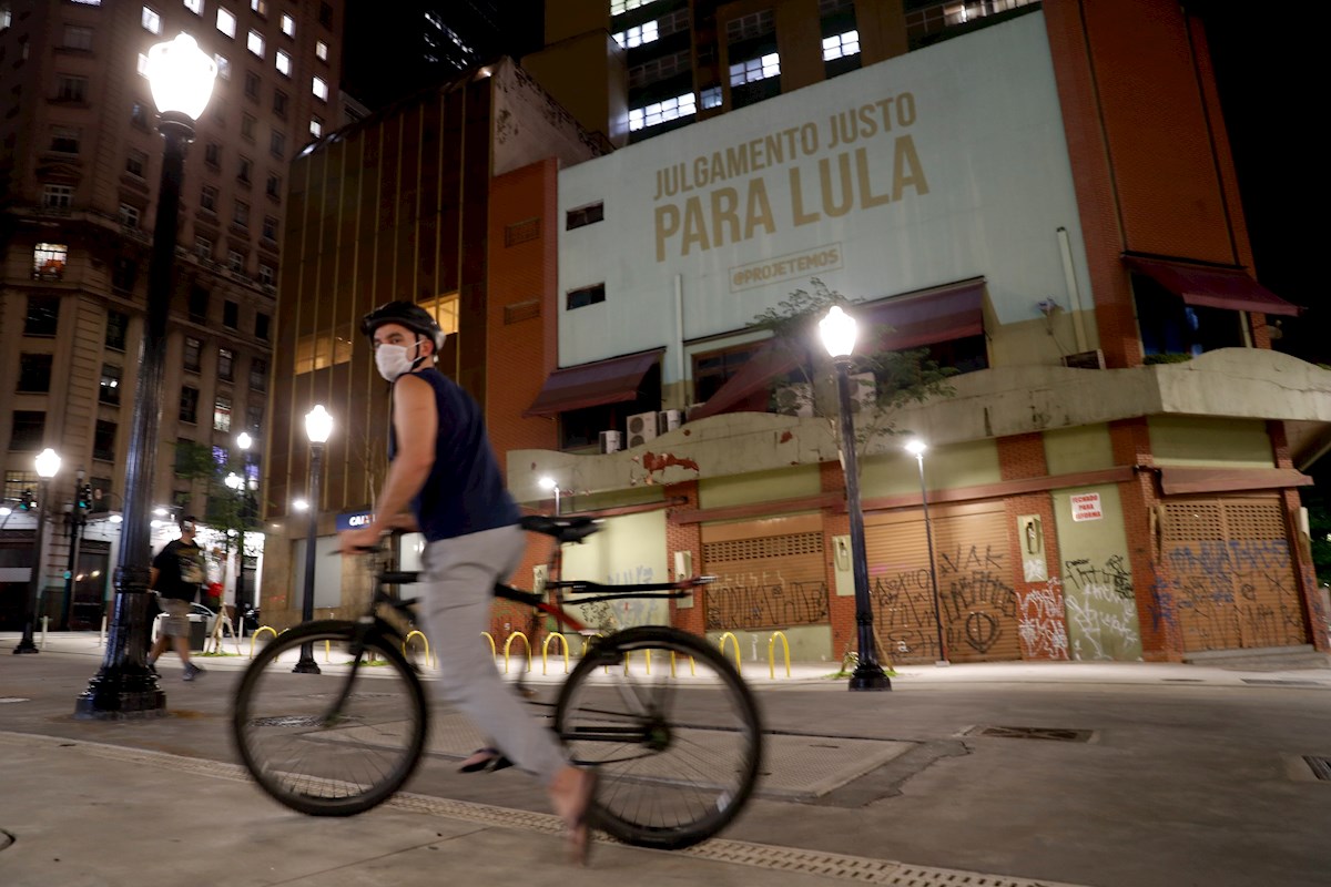 Un ciclista pasa frente a una proyección en favor del expresidente Luiz Inácio Lula da Silva, en el centro de Sao Paulo (Brasil). EFE/Fernando Bizerra