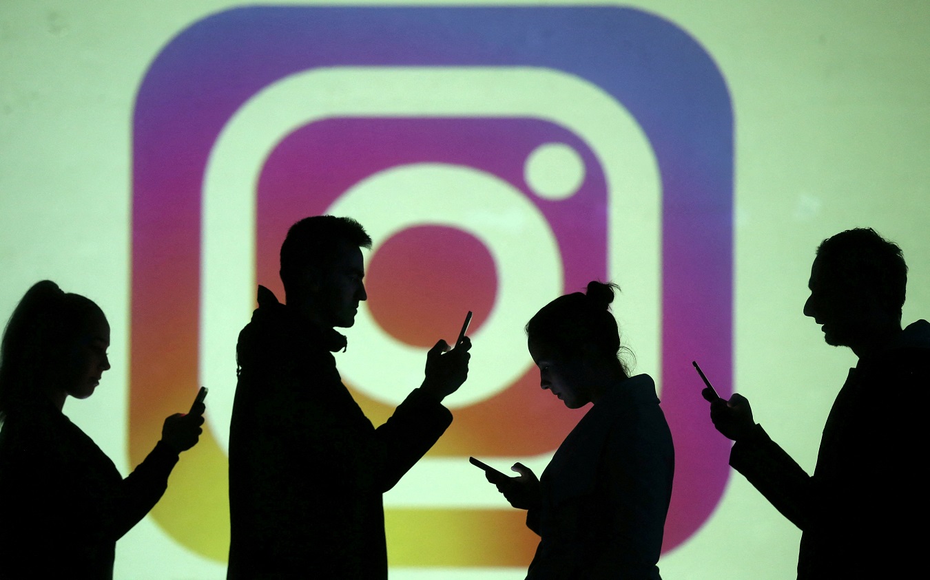 Siluetas de personas usando su 'smartphone' sobre un logo de la red social Instagram. REUTERS/Dado Ruvic/Illustration/