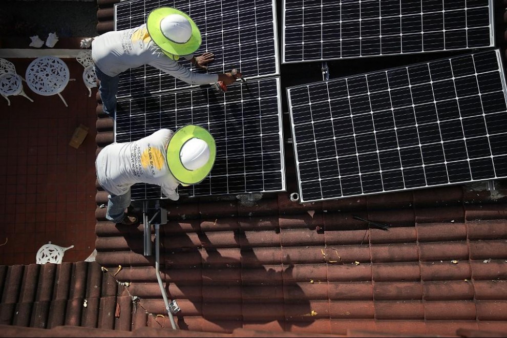 Dos operarios colocan paneles solares en el tejado de una vivienda. Foto: Joe Raedle / AFP