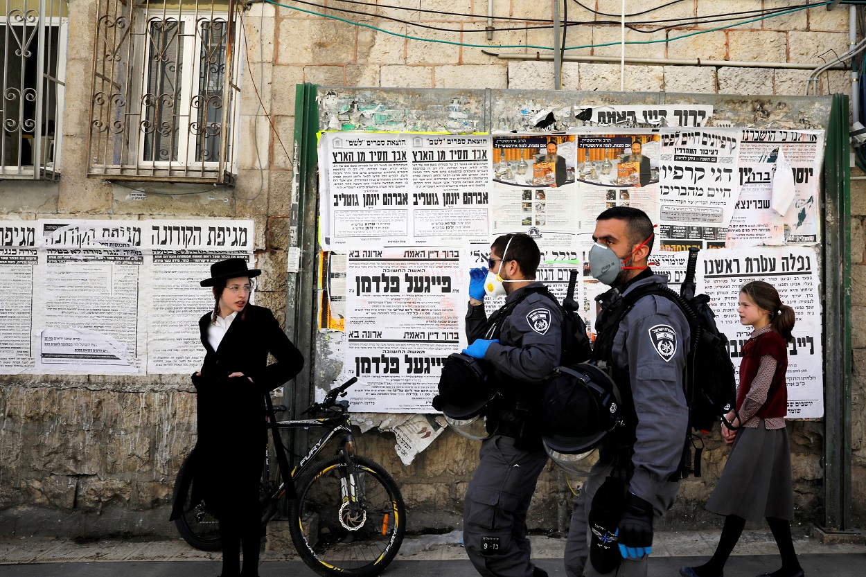 Policías israelíes con mascarillas patrullan por el bario de judios ultra-ortodoxos de Mea Shearim, en la zona norte de Jerusalén. REUTERS/Ronen Zvulun