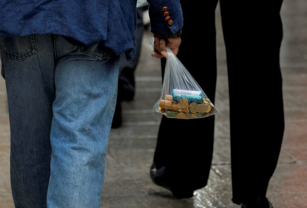Un home porta una bossa de plàstic amb noves monedes d'euro, el 15 de novembre del 2022. Foto: REUTERS/Jon Nazca
